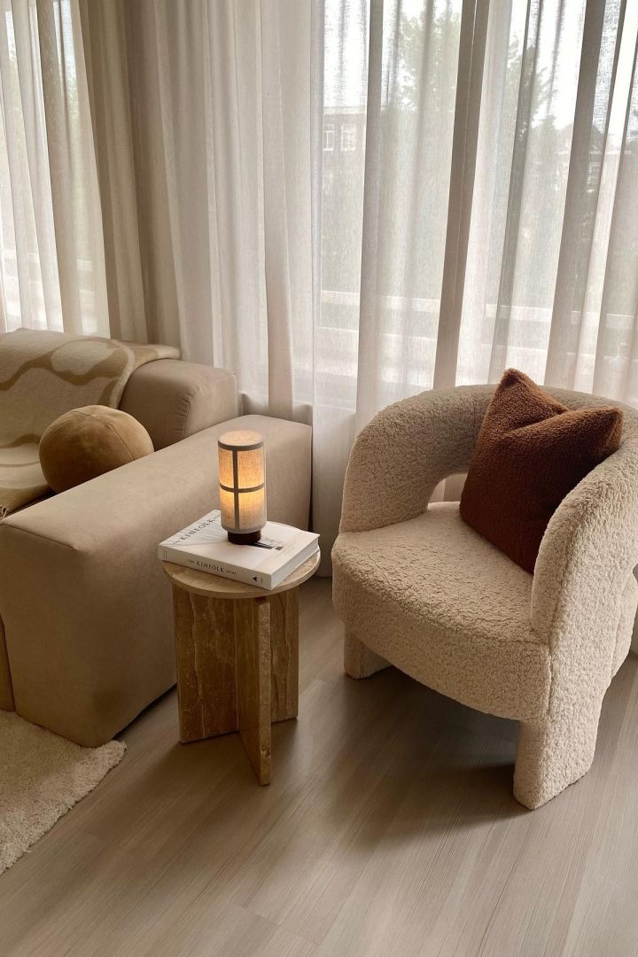 Portable lighting is a great idea for the living room lighting. Here you see the Hashira table lamp from Audo Copenhagen next to a boucle covered armchair. 