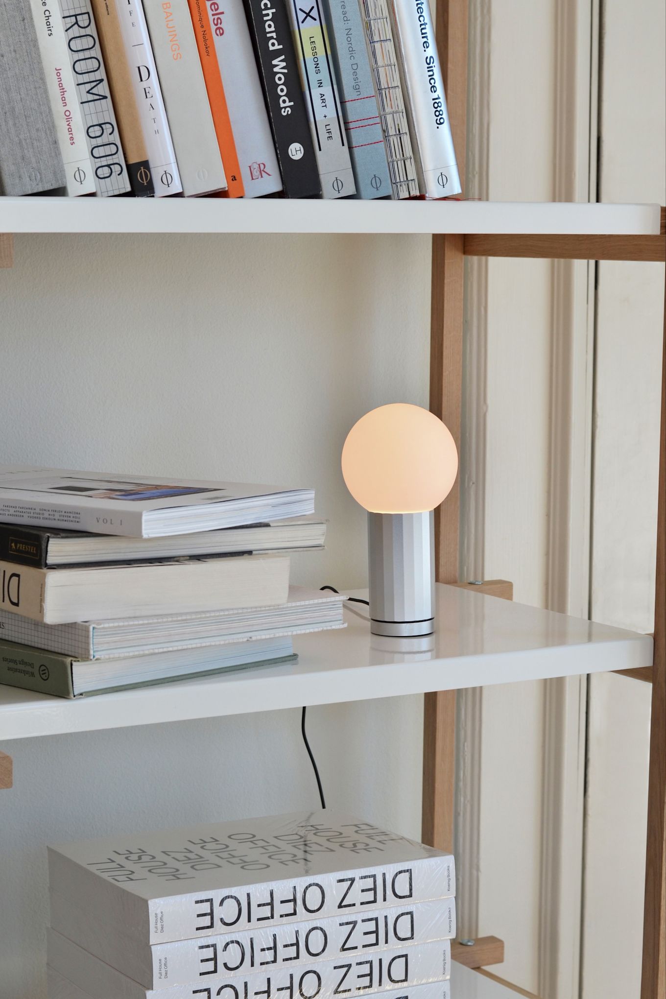 Atmospheric and accent lighting are also important in a home office environment. Here you see the Turn On lamp from HAY standing on a shelf surrounded by books. 