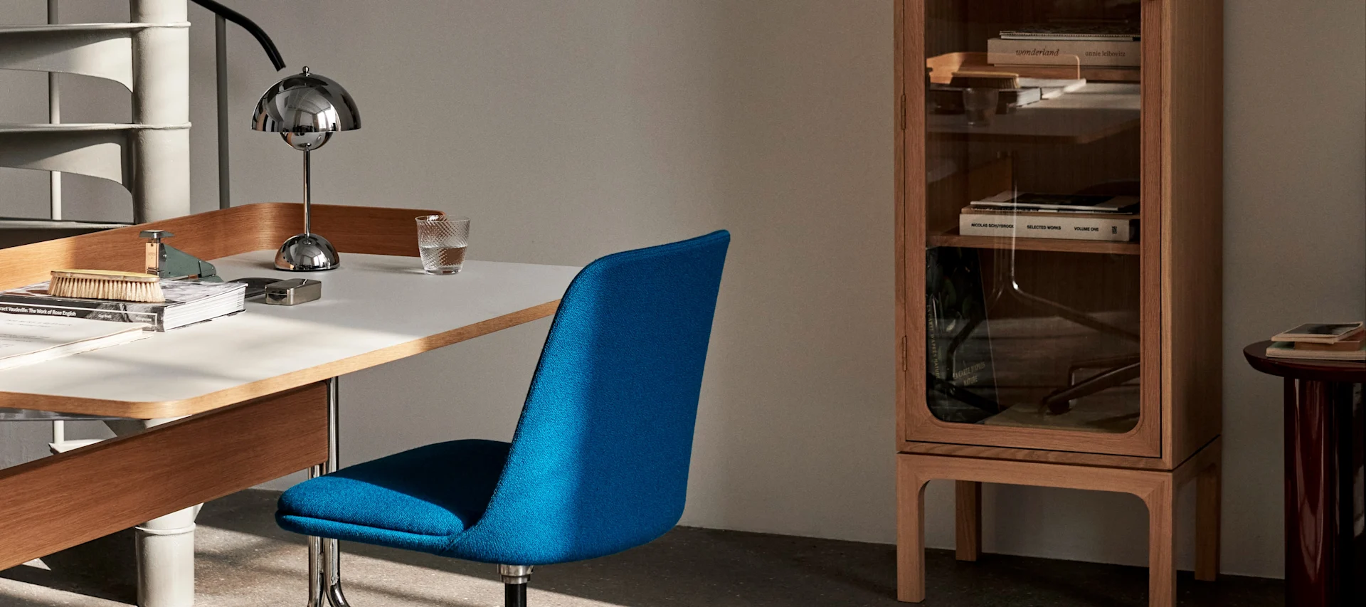 A home office with a blue chair and a chrome table lamp from &Tradition. The right lighting in the home office will make you more efficient and is also healthier.