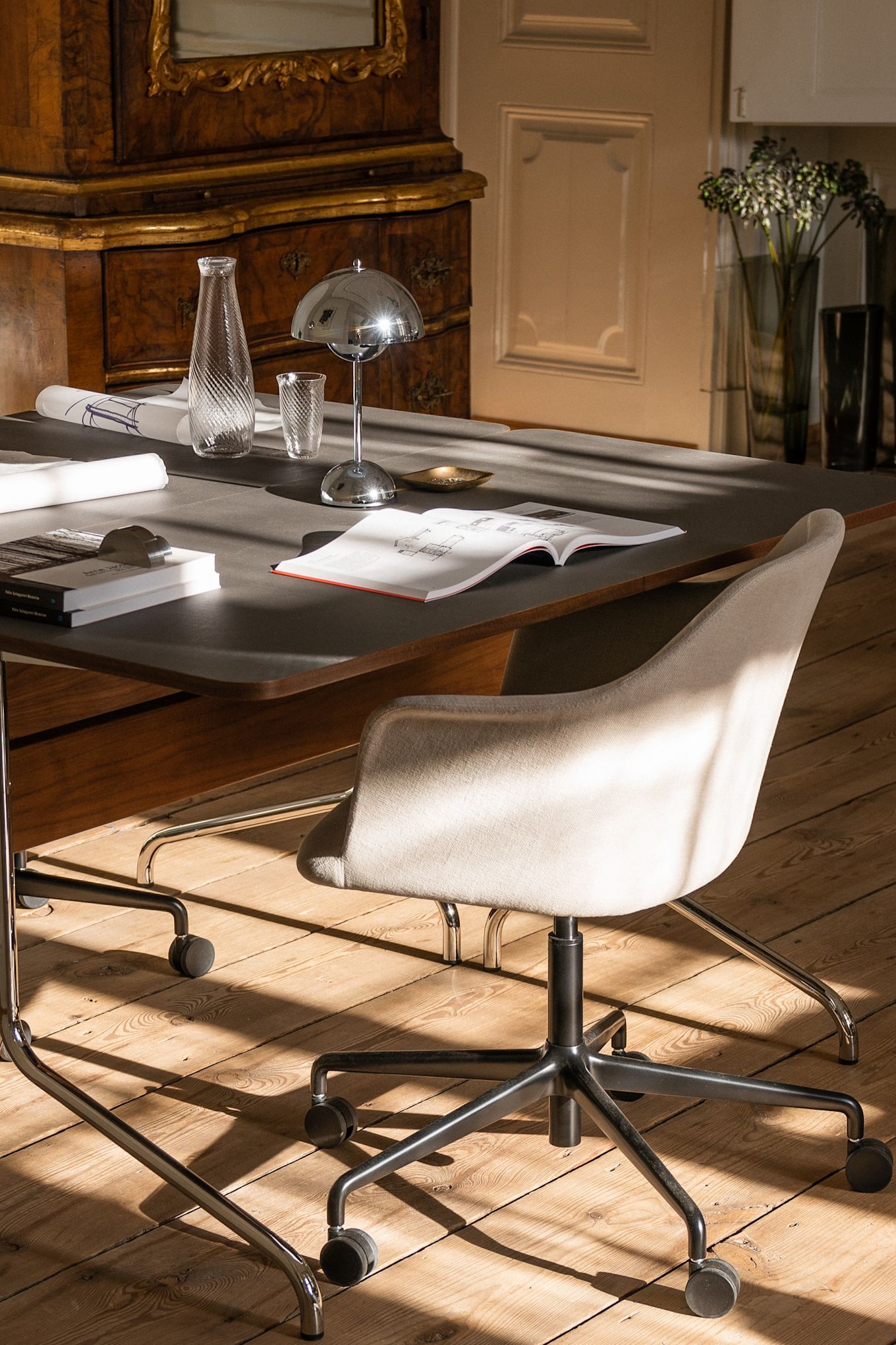 A chrome cordless table lamp from &Tradtion stands on a slightly cluttered desk in a grand home office. The right lighting for the home office is essential, here you see an office with lots of natural light. 