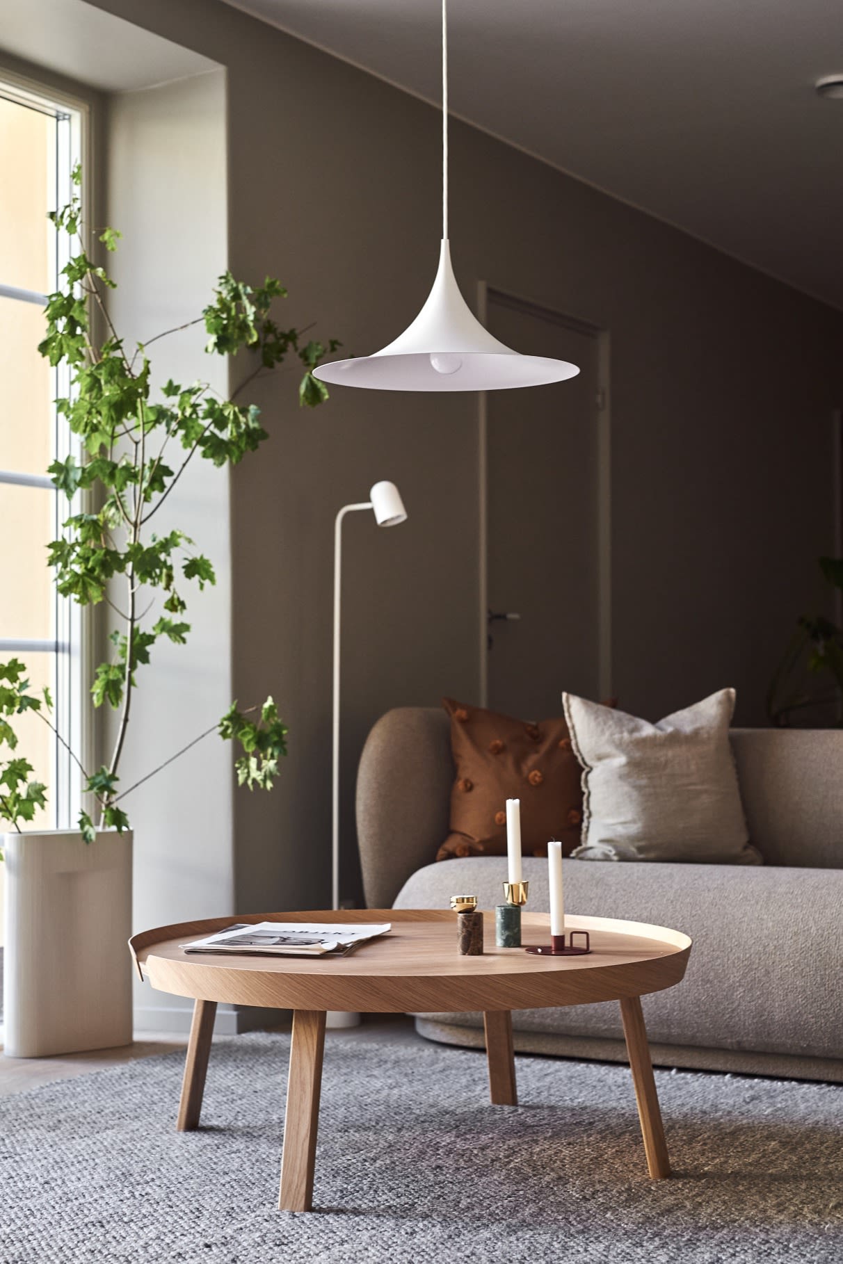 Lighting ideas for the living room include the hanging ceiling lamp Semi from Gubi with its curved shade seen here hanging over a coffee table. 