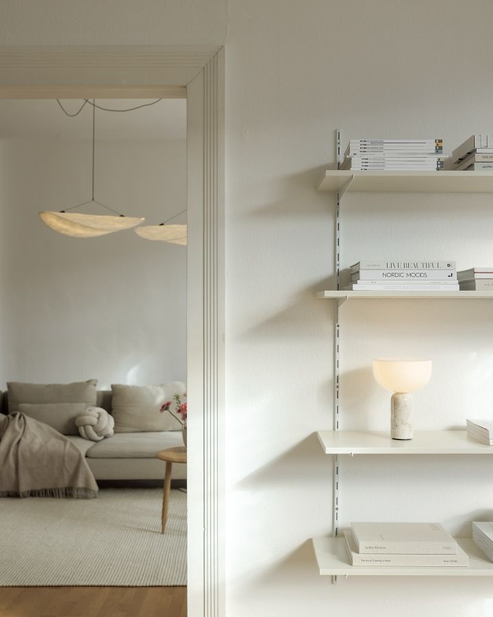 The Tense ceiling lamp from New Works hangs in a white living room with wooden accents. The perfect living room lighting idea for large and small living rooms. 