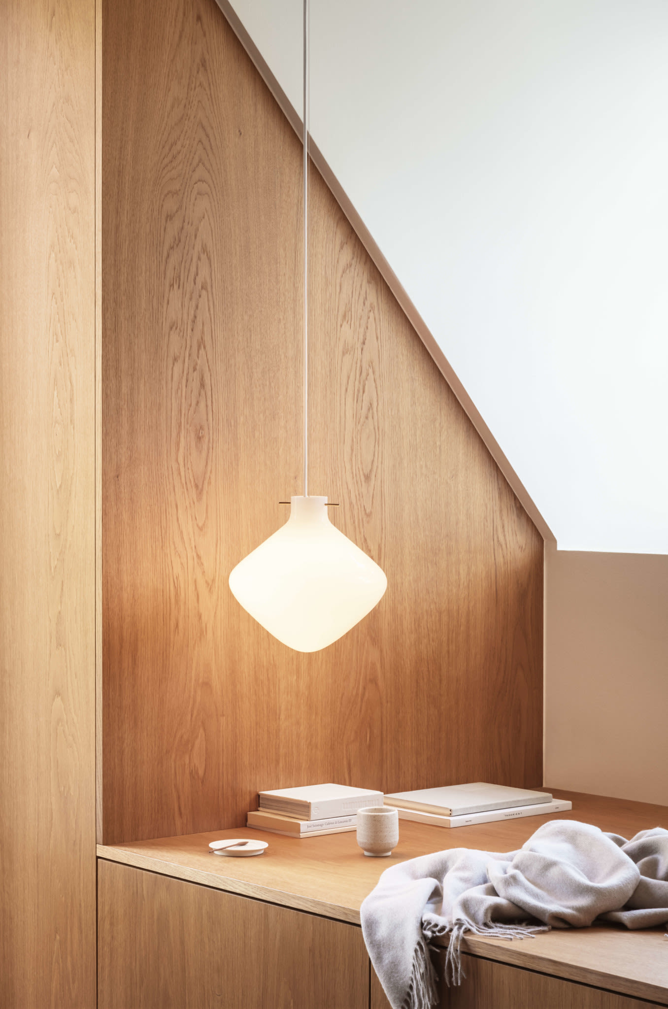 Living room lighting ideas include the Lyfa pendant lamp seen here hanging from the ceiling in wood panelled room. 